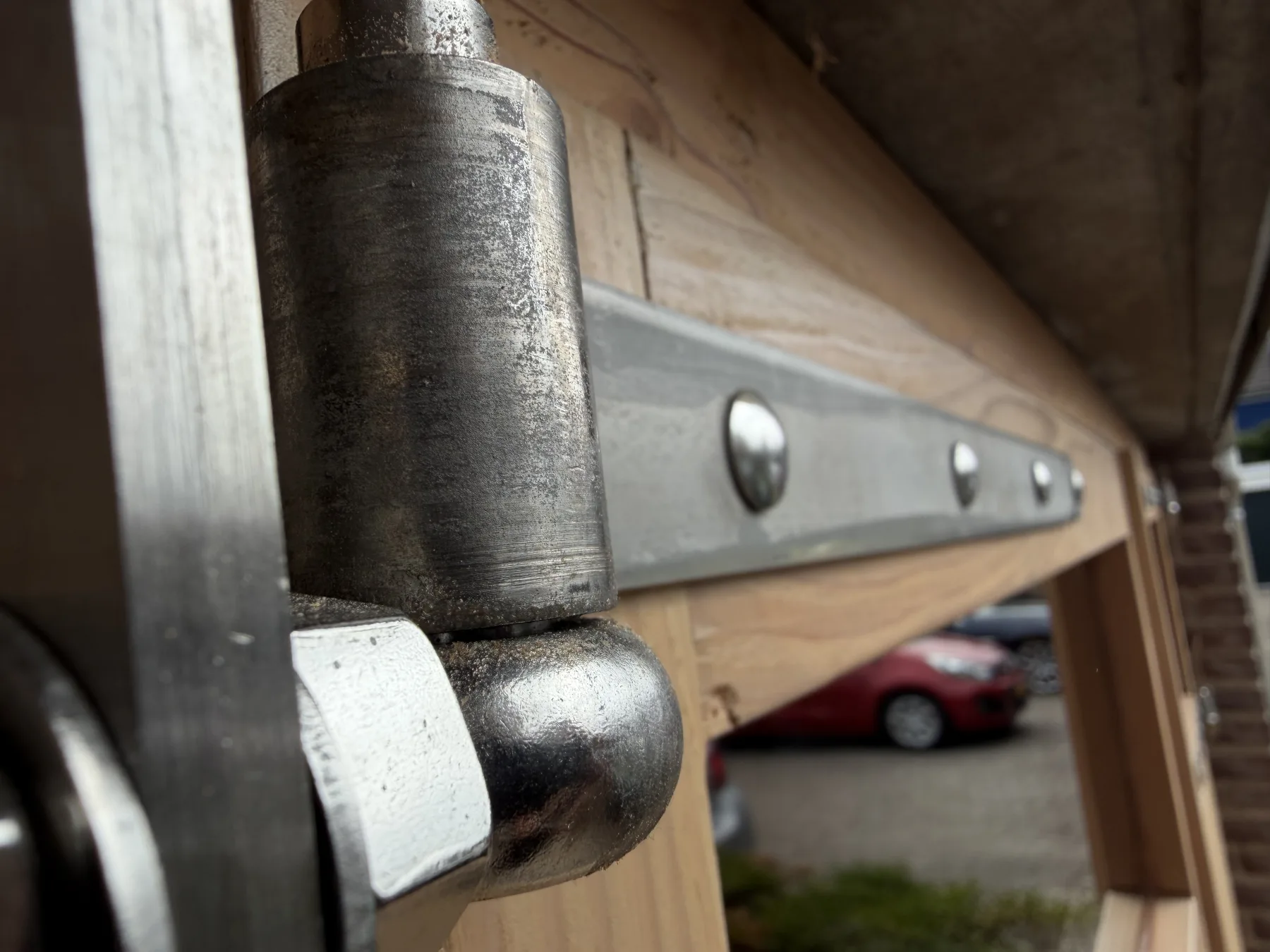 Close-up of the strap hinge on its pintle, with the glazing behind
