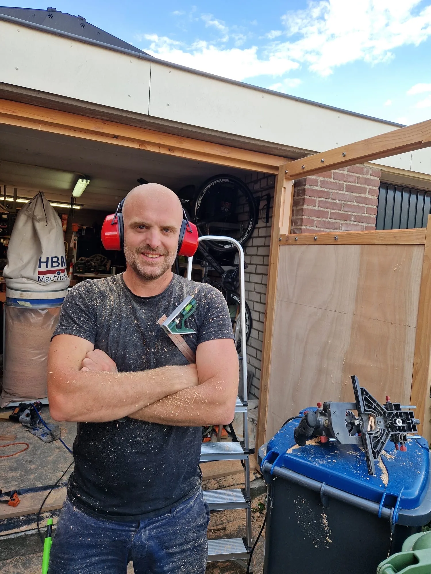 Bas Bartholomeus in front of the opened garage doors, wearing ear defenders