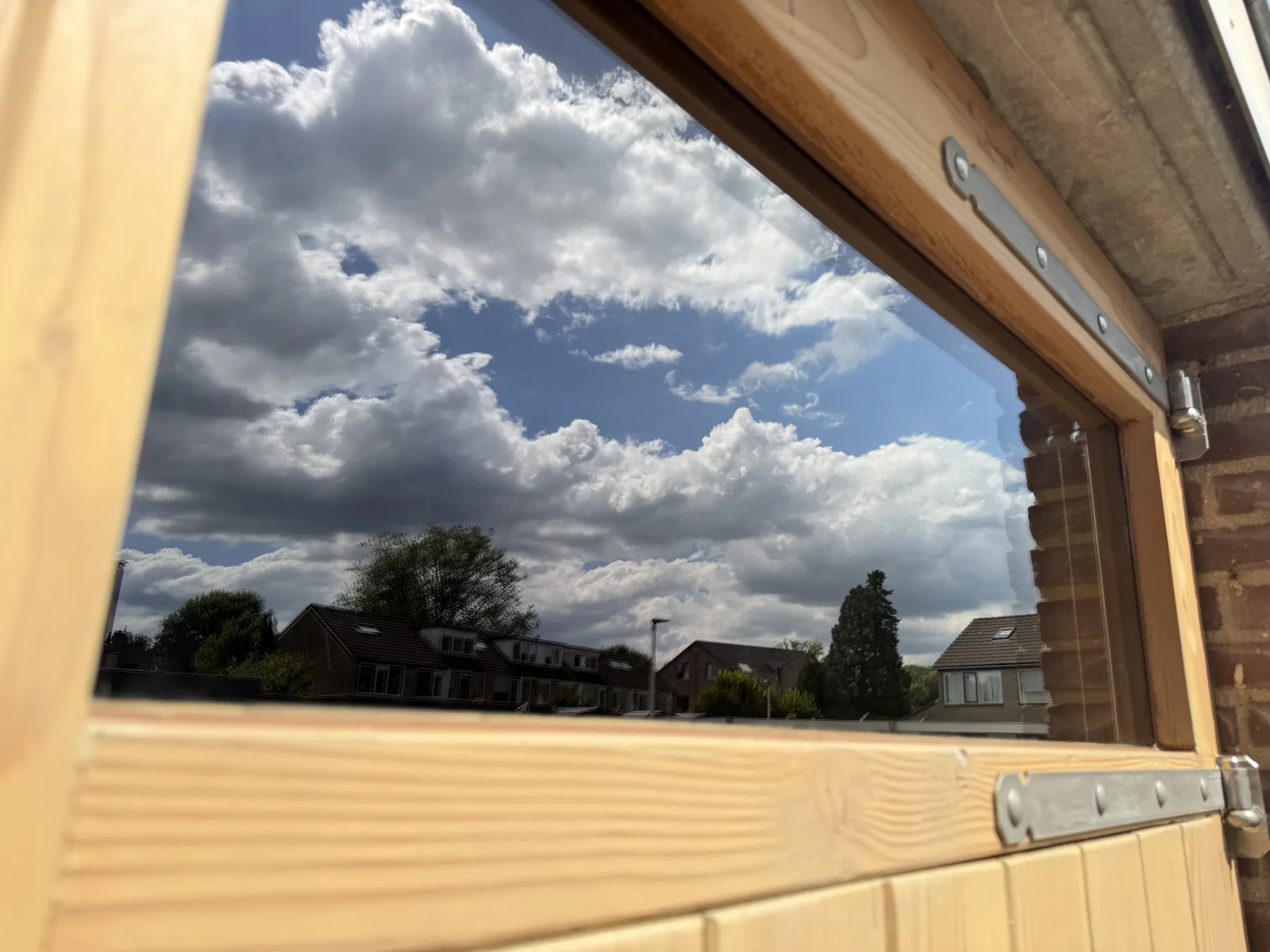 Wolkenlucht weerspiegeld in het glas van het bovenlicht, met de Douglas omlijsting