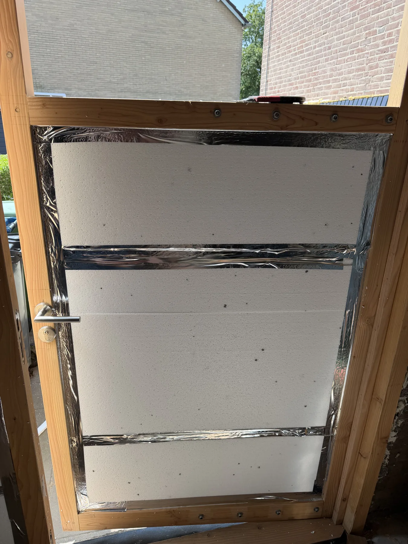 Insulation boards fitted between the rails of a door leaf, with the seams taped